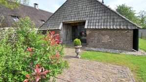 A traditional brick building with a tiled roof and a small garden area with a potted plant.