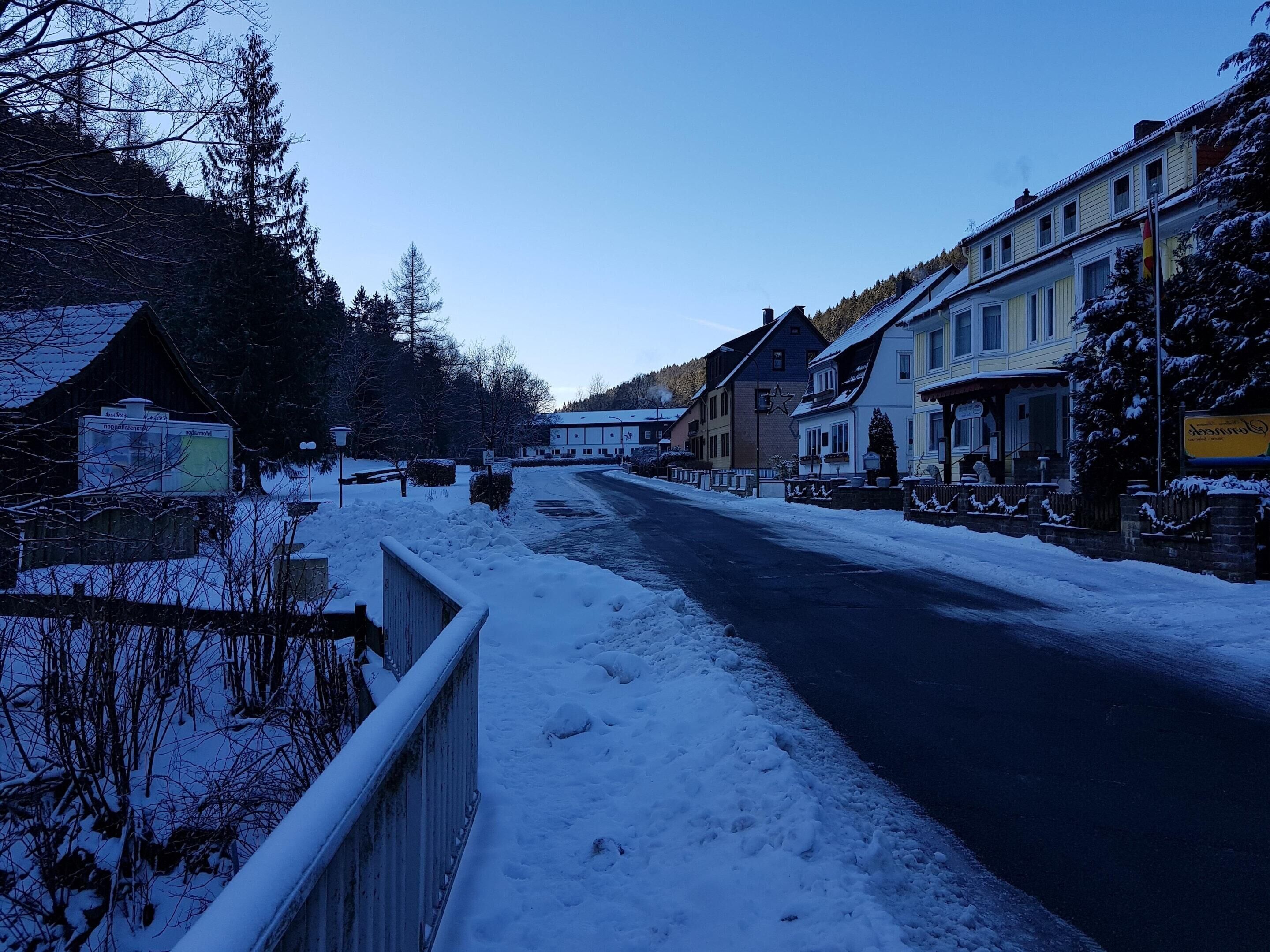 Eine verschneite Straße mit Gebäuden an beiden Seiten, darunter ein Hotel mit einem Stern-Schild.