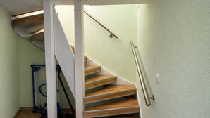 A staircase with wooden steps and a metal handrail, leading to a landing with a light switch. - Ski- und Wanderurlaub im Wald Ferienhaus Adlerblick (Masserberg)