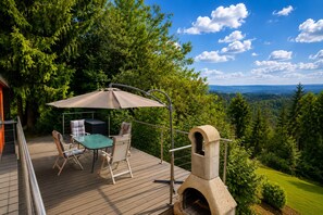Une terrasse dotée de mobilier d’extérieur, d’un barbecue et offrant une vue magnifique.