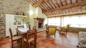 A rustic dining area with a stone wall, wooden ceiling beams, and a fireplace. - Idyllic Stay With Charm (Monte Santa Maria Tiberina)