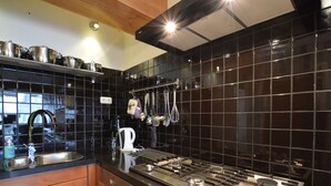 A modern kitchen with black tiles, stainless steel appliances, and wooden cabinets. - Beautiful Farmhouse in Wapse With Fenced Garden (Wapse)