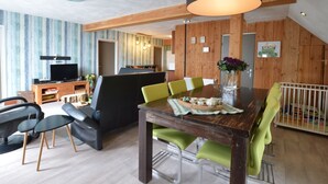A modern dining area with a wooden table, green chairs, and a black pendant light. - Beautiful Farmhouse in Wapse With Fenced Garden (Wapse)