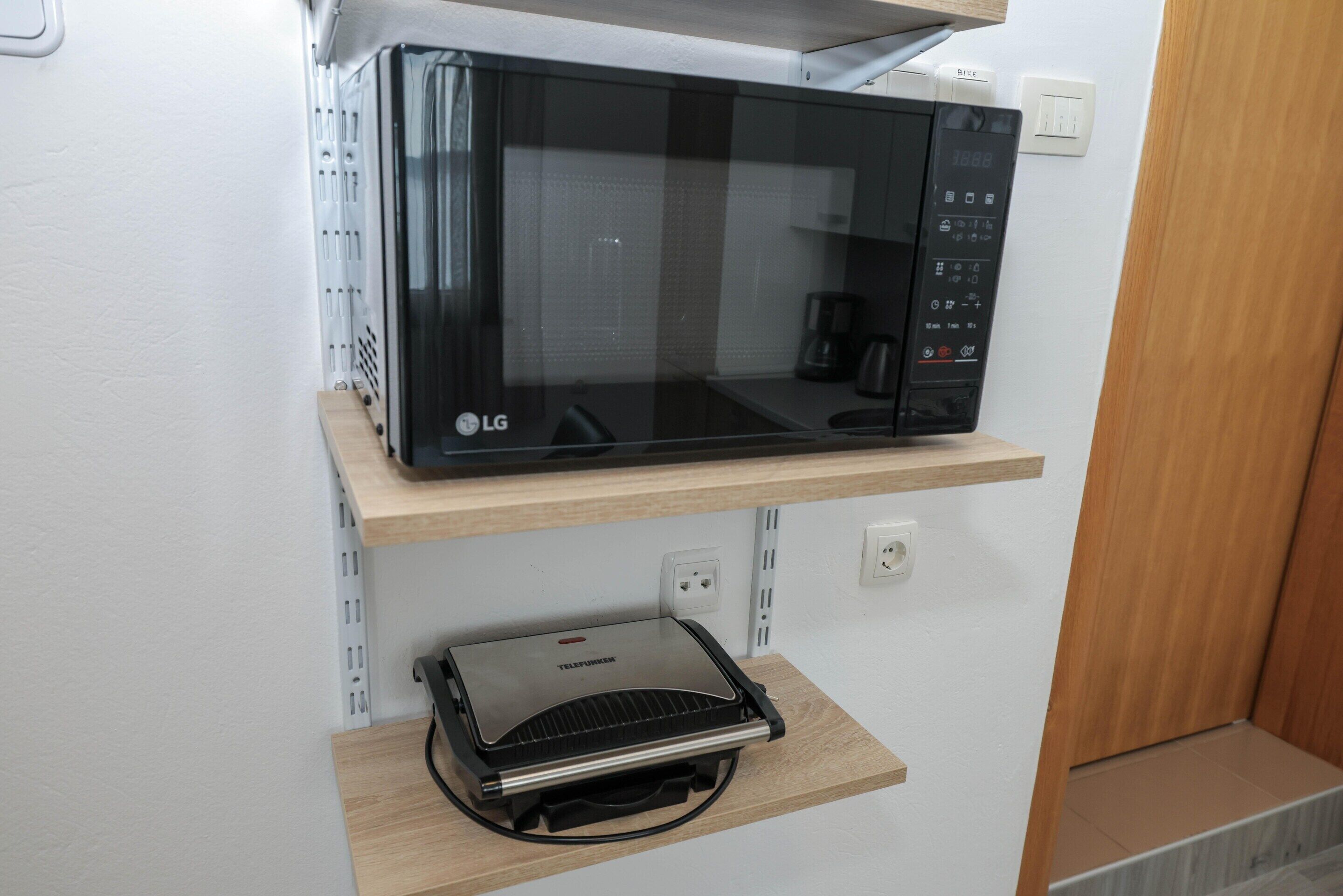 Un forno a microonde su uno scaffale sopra un termosifone portatile.