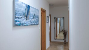A hallway with a painting of sailboats on the wall, a wooden door, and a mirror reflecting the hallway. - Peace & Sun Await in Dalmatia (Starigrad)