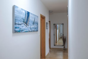 A hallway with a painting of sailboats on the wall, a wooden door, and a mirror reflecting the hallway. - Peace & Sun Await in Dalmatia (Starigrad)