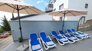 A rooftop terrace with sun loungers and umbrellas, a staircase, and a view of a car and trees. - Peace & Sun Await in Dalmatia (Starigrad)