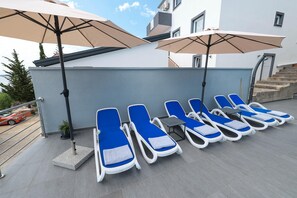 A rooftop terrace with sun loungers and umbrellas, a staircase, and a view of a car and trees. - Peace & Sun Await in Dalmatia (Starigrad)