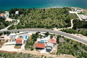An aerial view of a coastal area with a curved road, residential buildings, and a beach. - Peace & Sun Await in Dalmatia (Starigrad)