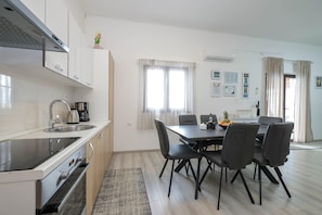 A modern kitchen with stainless steel appliances, a dining area with a table and chairs, and a living space with a sofa and a coffee table. - Peace & Sun Await in Dalmatia (Starigrad)