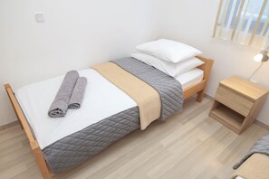 A single bed with a quilted bedspread, two rolled towels, and a bedside table with a lamp. - Peace & Sun Await in Dalmatia (Starigrad)