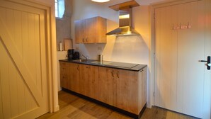 A compact kitchen with wooden cabinets, a stainless steel sink, and a modern overhead light fixture. - Romantic Farmhouse Escape (Geesteren)