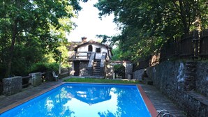 A rectangular swimming pool with a stone border, surrounded by a stone wall and a wooden fence. - Peaceful Retreat With Shared Pool (San Marcello Piteglio)