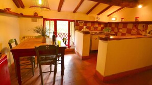 A cozy dining area with a wooden table and chairs, a kitchen with a checkered backsplash, and a hanging light fixture. - Peaceful Retreat With Shared Pool (San Marcello Piteglio)