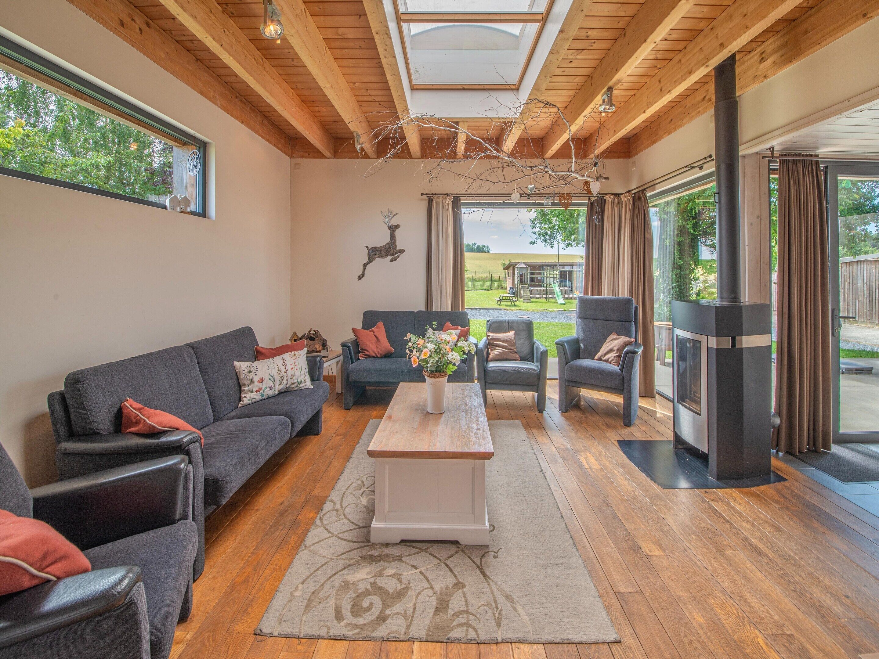 Un salon chaleureux avec un plafond en bois, une cheminée et une vue sur un terrain de jeux.
