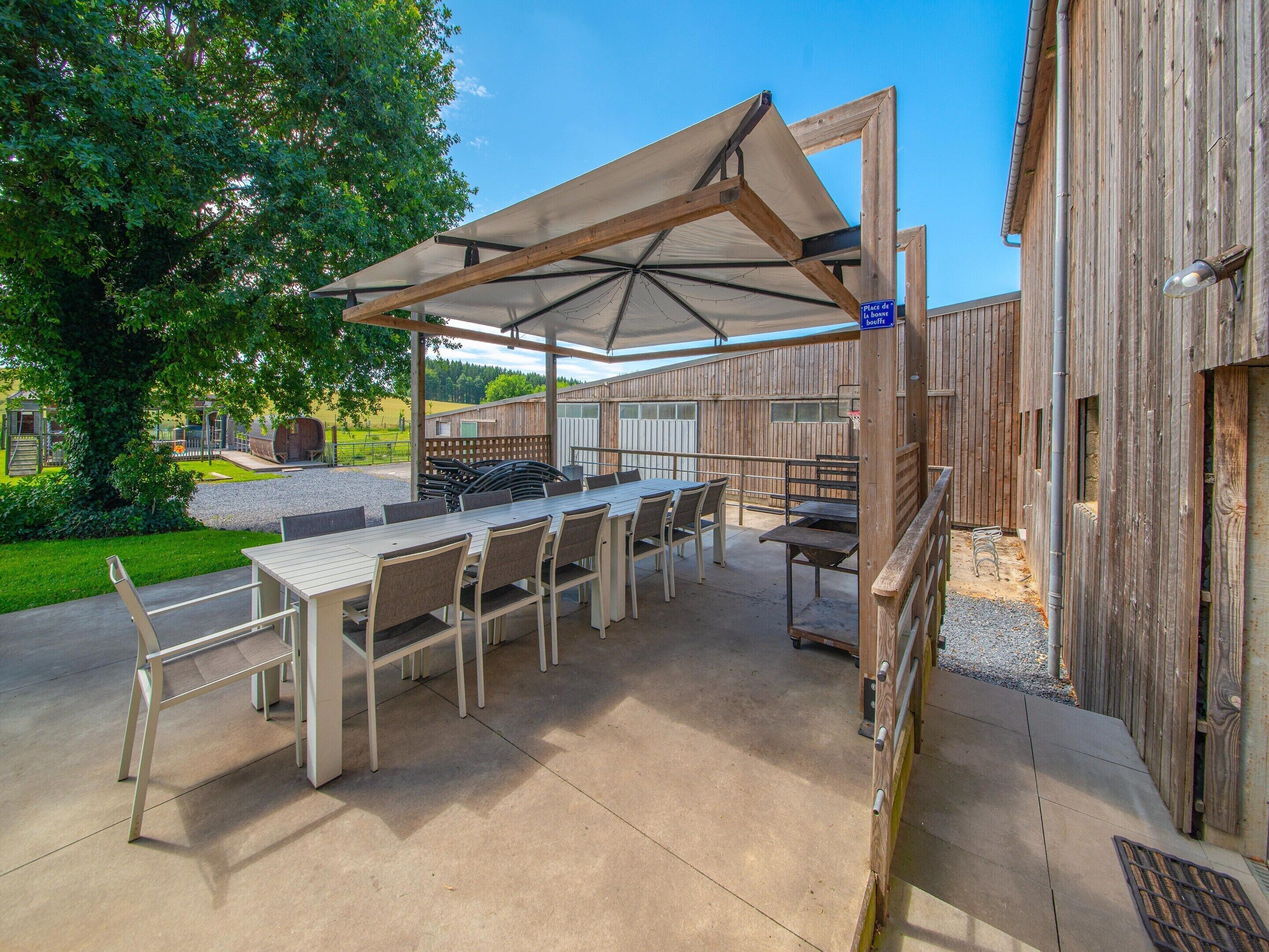 An outdoor patio with a table and chairs, a barbecue grill, and a covered seating area.