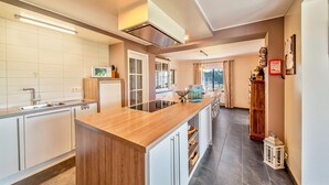 Een moderne keuken met een houten kookeiland, witte kasten en een ingebouwde oven.