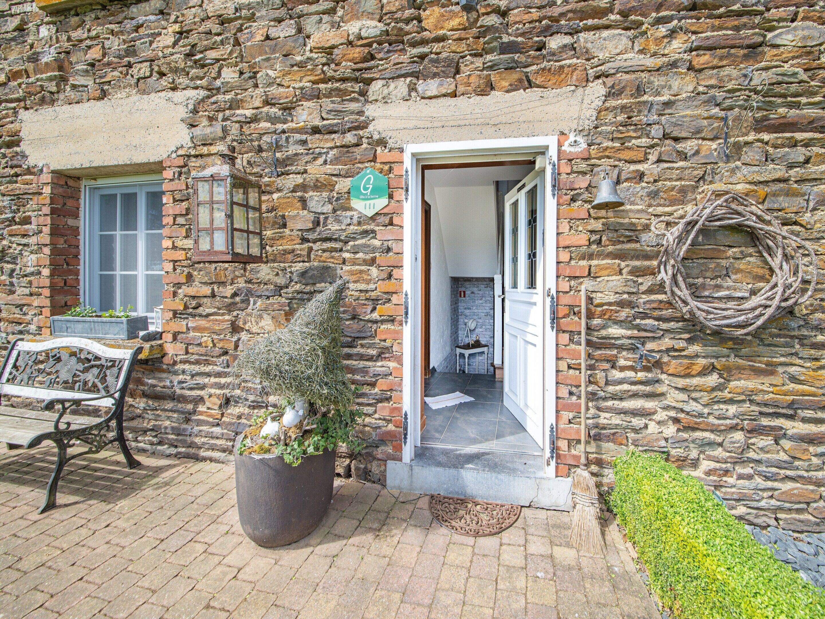A stone building with a door leading to a room, a bench, and a potted plant.