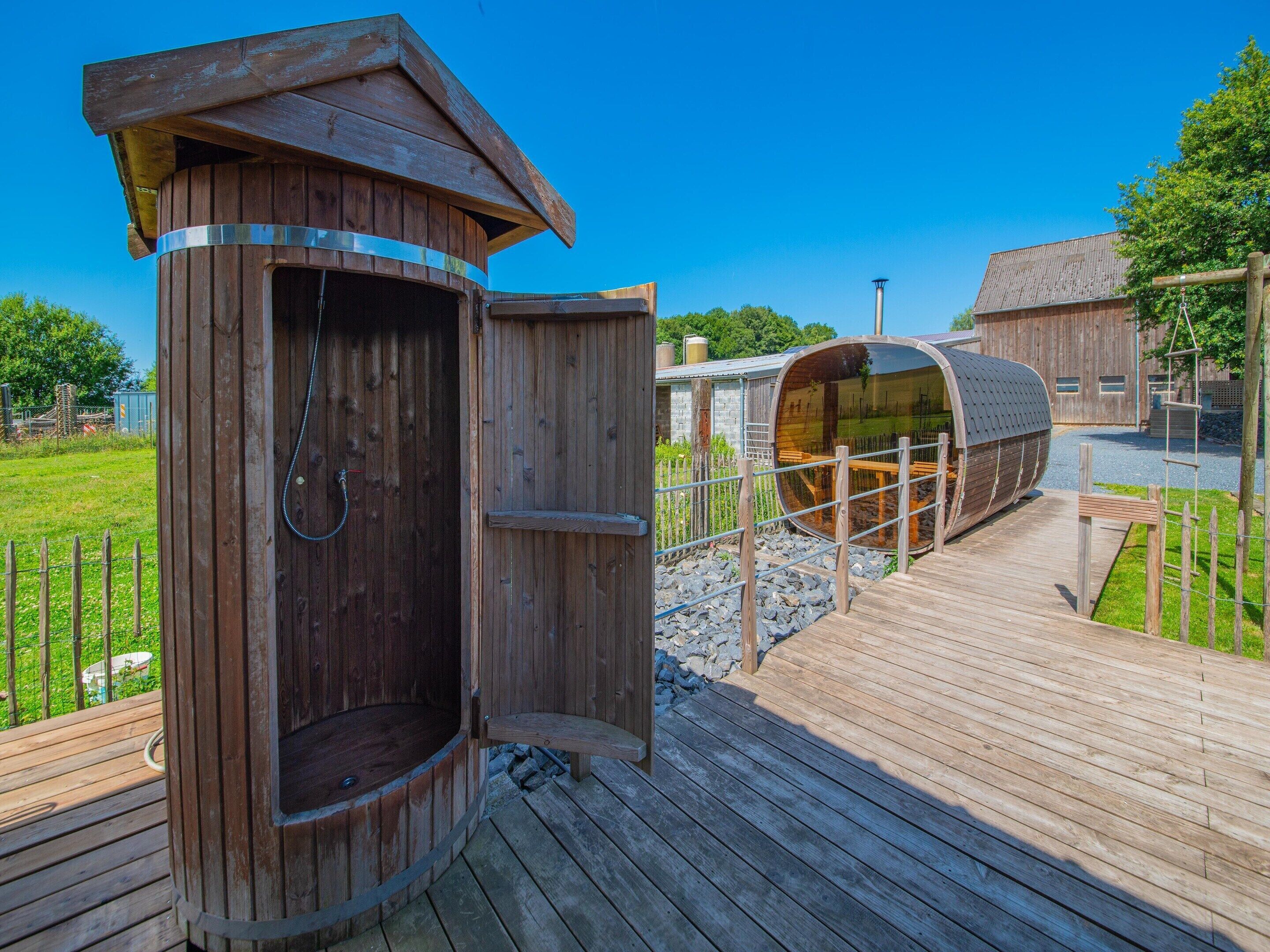 Un petit bâtiment en bois servant de toilettes, avec une porte en métal et une terrasse en bois.