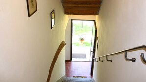 A staircase with a wooden handrail, a door leading outside, and a small potted plant visible through the door. - Restful Farmhouse with Pool near Forest in Vinci (Vinci)