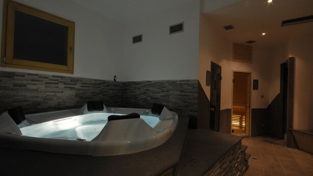 A spa area with a hot tub, stone wall, and a staircase leading to another room. - Holiday Home in Caldes Near Ski Lift (Caldes)
