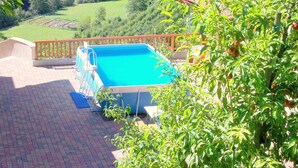 A rectangular swimming pool with a wooden deck and a metal ladder, surrounded by a wooden fence. - Holiday Home in Caldes Near Ski Lift (Caldes)