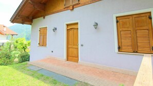 A two-story building with wooden shutters, a brick entrance, and a small porch. - Holiday Home in Caldes Near Ski Lift (Caldes)
