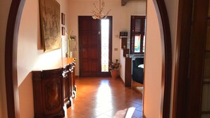 A hallway with a wooden bench, a chandelier, and a door leading to another room. - Belvilla by OYO Serena (Massa)