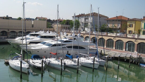 A marina with several yachts docked, surrounded by buildings with arched windows and balconies. - A Serene Stay in Gemmano (Gemmano)