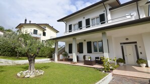 A two-story house with a covered porch, outdoor seating, and a well-maintained garden. - A Serene Stay in Gemmano (Gemmano)