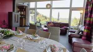 Un comedor con una mesa preparada para comer, un sofá y vistas al exterior.