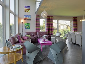 A modern living room with a leather sofa, a dining area with wicker chairs, and artwork on the walls. - Ovifat Sauna Escape, Waimes (Waimes)
