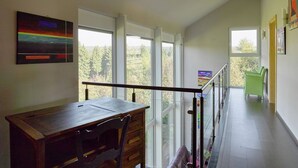 Una habitación amplia con un escritorio de madera, una silla y un balcón con barandilla.