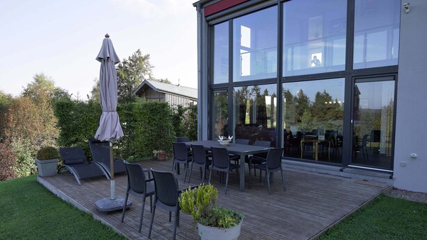 Un patio con una mesa, sillas, una planta en maceta y una sombrilla.