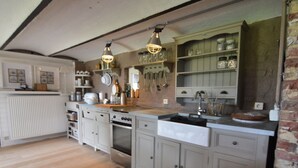 A kitchen with white cabinetry, a wooden countertop, and hanging utensils. - Pleasant Holiday Home in West Flanders with Enclosed Garden & Hot Tub (Pittem)