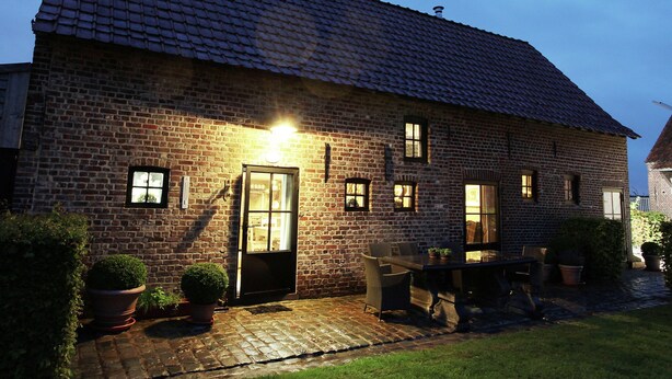 A brick house with a tiled roof, a front door, and a small patio area with a table and chairs. - Pleasant Holiday Home in West Flanders with Enclosed Garden & Hot Tub (Pittem)