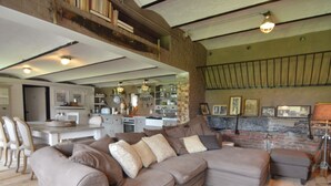 A spacious living area with a large sectional sofa, a dining table, and a kitchen in the background. - Pleasant Holiday Home in West Flanders with Enclosed Garden & Hot Tub (Pittem)