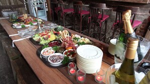 A wooden table set with various food items, plates, and bottles of champagne. - Pleasant Holiday Home in West Flanders with Enclosed Garden & Hot Tub (Pittem)