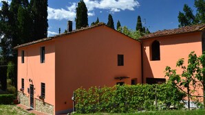 A two-story building with a peach-colored facade, a stone foundation, and a tiled roof.