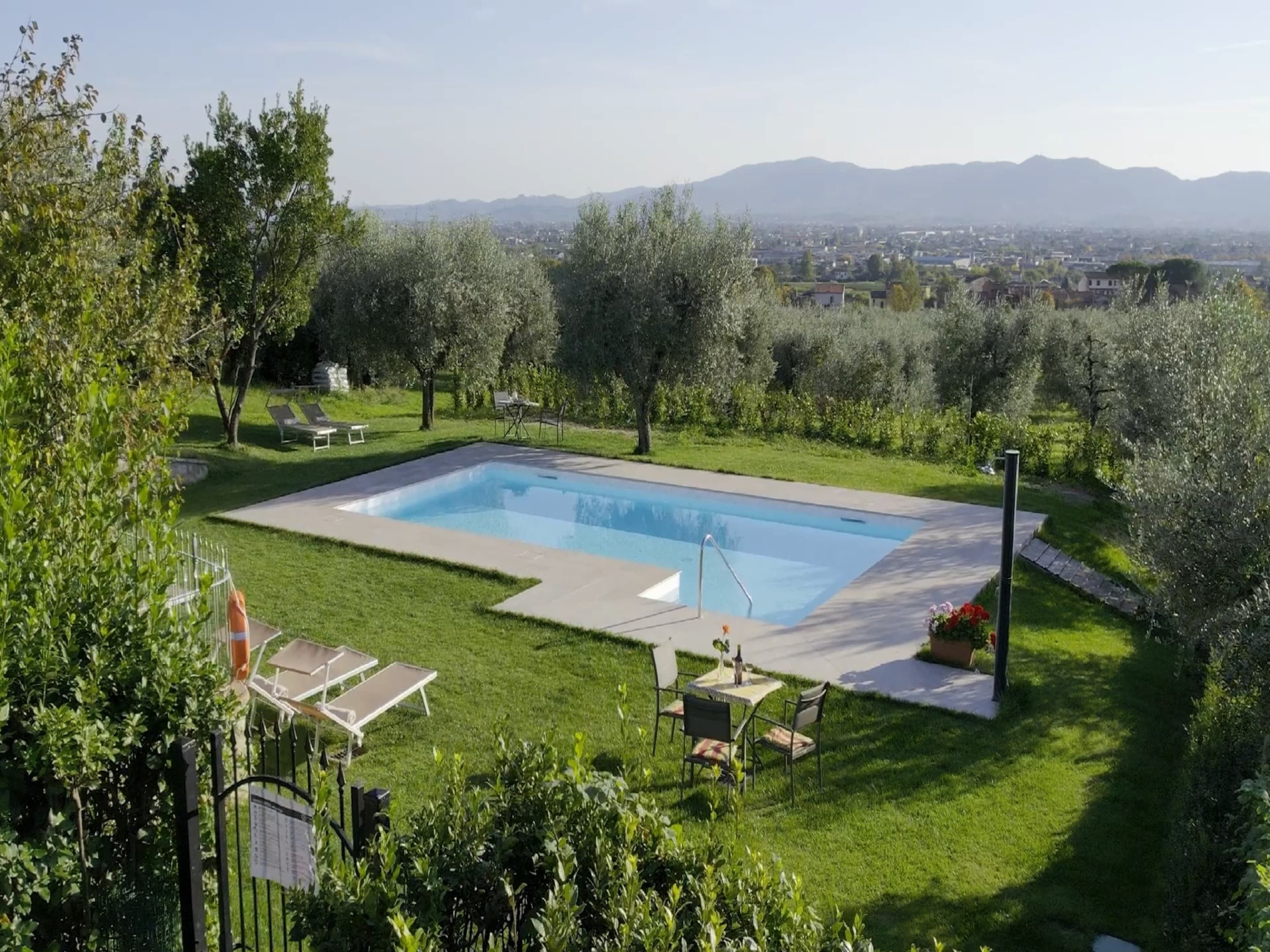 Une piscine rectangulaire entourée d’une pelouse bien entretenue, d’où l’on peut admirer des montagnes lointaines.