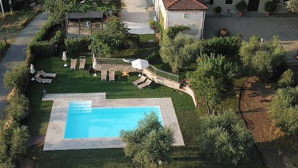 An aerial view of a residential area with a swimming pool, lounge chairs, and a small garden.