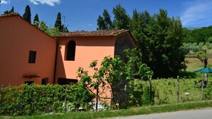 A building with a peach-colored facade, a small arched window, and a tiled roof.