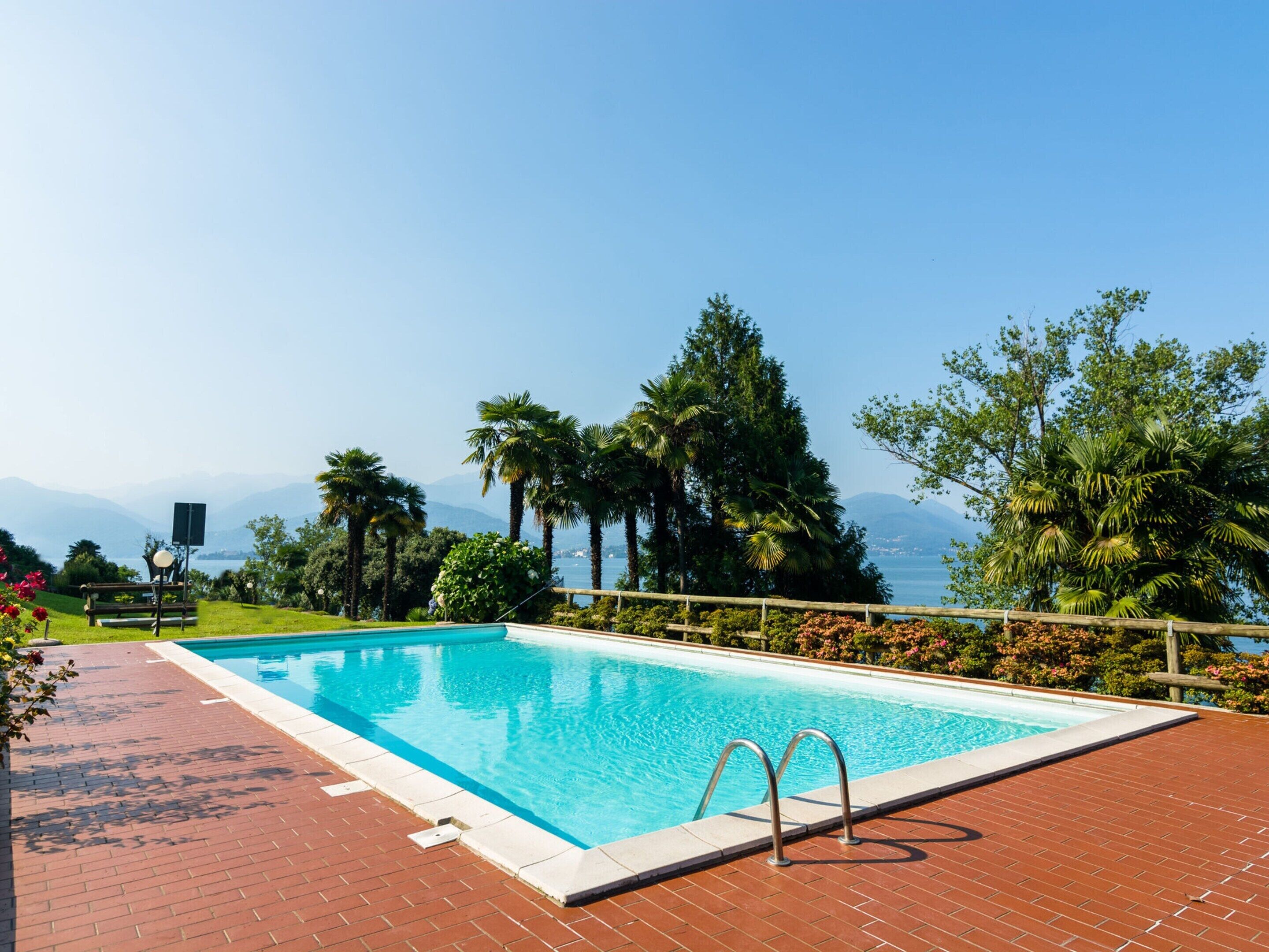 A rectangular swimming pool with a clear blue water surface, surrounded by a brick deck.