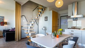 Una cucina moderna con piano cottura a gas, un tavolo da pranzo con sedie e una scala dal design originale.