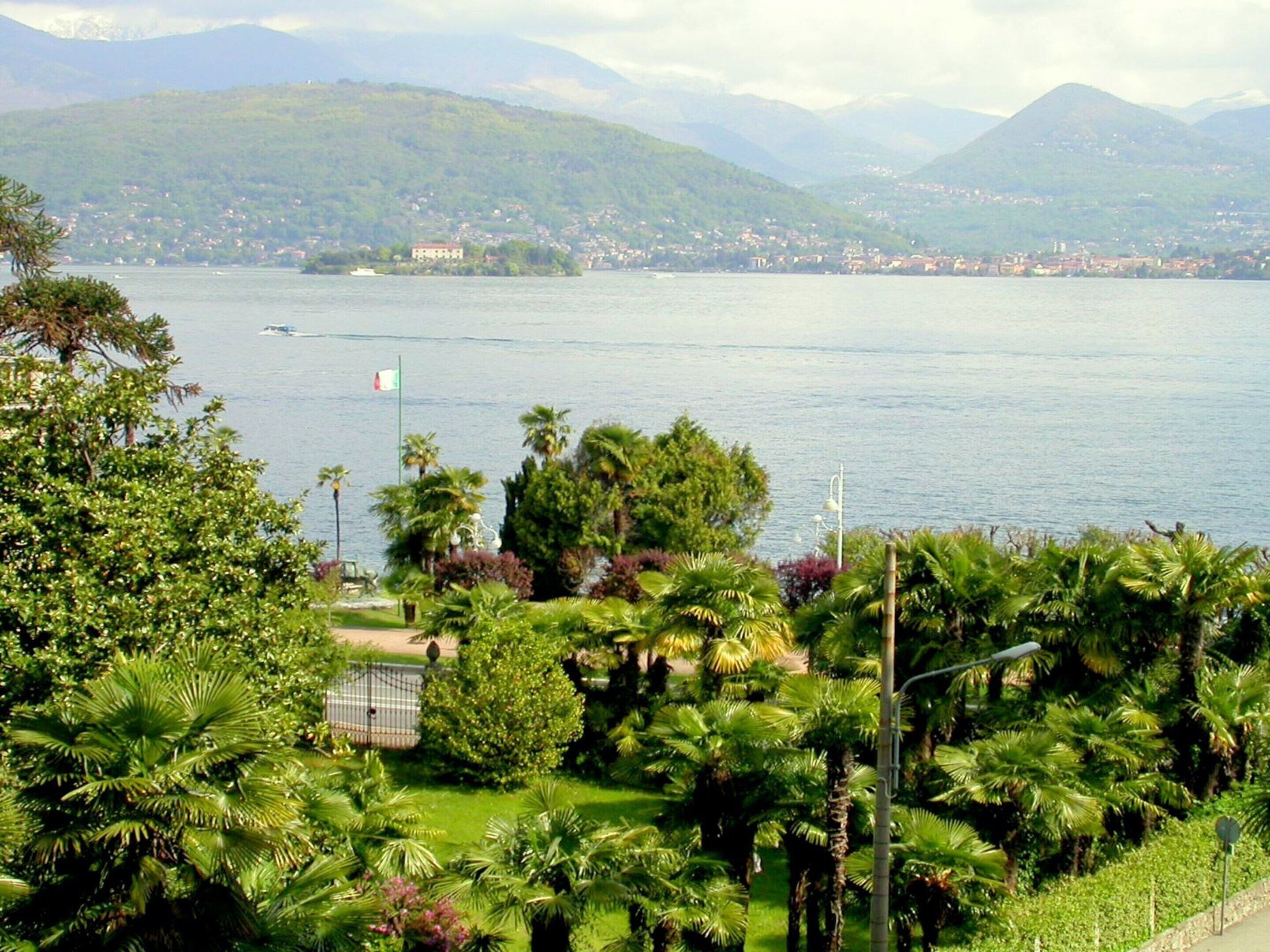 A coastal landscape with a view of a lake, mountains, and a flag.