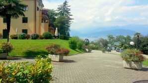 Un hotel con un viale lastricato che conduce a un edificio con balconi, immerso nel verde curato e con vista sulle montagne.