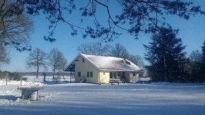 A small, single-story building with a sloped roof, surrounded by snow-covered ground and trees. - Family Residence With Large Garden (Heino)