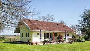 A single-story house with a red-tiled roof, a covered patio with outdoor seating, and a well-maintained lawn. - Family Residence With Large Garden (Heino)