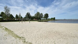 A sandy beach with a swing set and trees in the background. - Charming Apartment in Langweer With Jetty (Langweer)