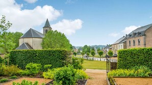A garden with a pathway leading to a building with a tower. - Beautiful Villa With Sauna in Chiny (Chiny)